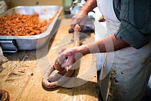 Man making sausages the traditional way using sausage filler.