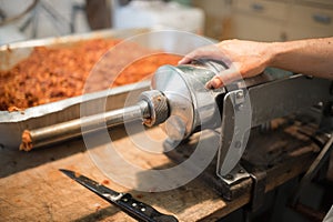 Man making sausages the traditional way using sausage filler.