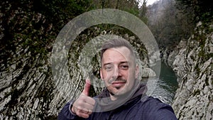 Man making selfie and showing thumb up at Canyon Devil`s Gate in Sochi, Russia.