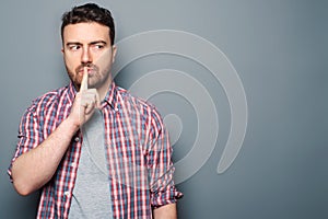 Man making silence gesture on gray background