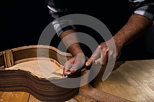 Man making a spanish guitar. Hands working wood