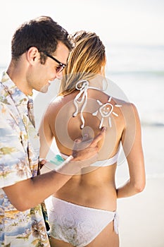 Man making a sun symbol on womans back while applying a sunscreen lotion