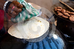 Man making an ulta tawa paratha bread on an upturned pot mughal cuisine from india and pakistan