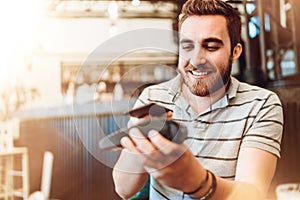 Smiling man making a wireless payment, customer using mobile phone, device with nfc technology for paying the bill