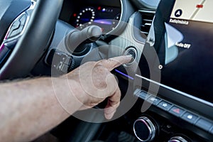 Man male finger pressing the Engine start stop button of a car