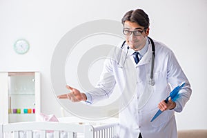 The man male pediatrician near baby bed preparing to examine