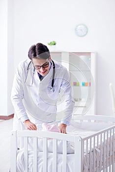 The man male pediatrician near baby bed preparing to examine