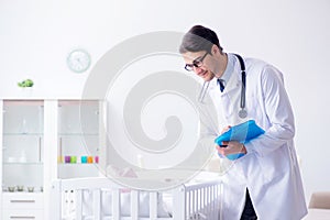 The man male pediatrician near baby bed preparing to examine