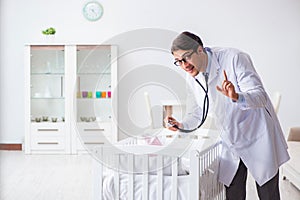 The man male pediatrician near baby bed preparing to examine