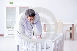 The man male pediatrician near baby bed preparing to examine