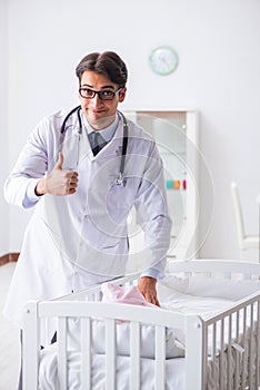 The man male pediatrician near baby bed preparing to examine