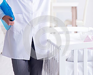 Man male pediatrician near baby bed preparing to examine