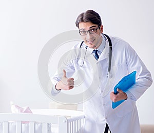 Man male pediatrician near baby bed preparing to examine