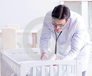 Man male pediatrician near baby bed preparing to examine