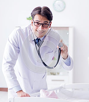 Man male pediatrician near baby bed preparing to examine