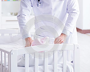 Man male pediatrician near baby bed preparing to examine