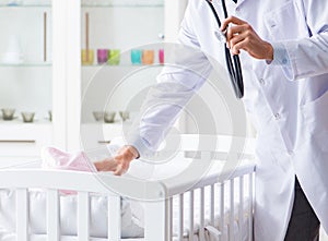 Man male pediatrician near baby bed preparing to examine