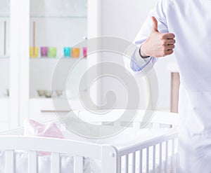 Man male pediatrician near baby bed preparing to examine