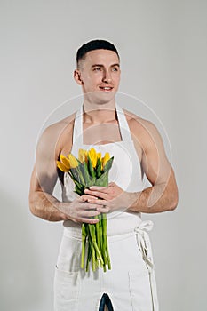 Man man with naked torso in apron gives flowers. Romantic Man with bouquet of tulips for birthday. Happy woman`s day