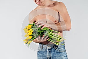 Man man with naked torso gives flowers. Romantic Man with bouquet of tulips for birthday. Happy woman`s day. Giving