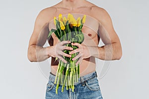 Man man with naked torso gives flowers. Romantic Man with bouquet of tulips for birthday. Happy woman`s day. Giving