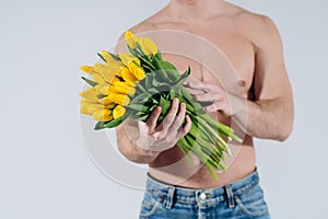 Man man with naked torso gives flowers. Romantic Man with bouquet of tulips for birthday. Happy woman`s day. Giving