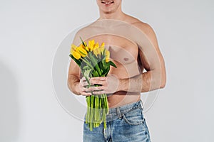 Man man with naked torso gives flowers. Romantic Man with bouquet of tulips for birthday. Happy woman`s day. Giving