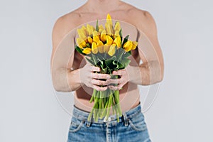 Man man with naked torso gives flowers. Romantic Man with bouquet of tulips for birthday. Happy woman`s day. Giving