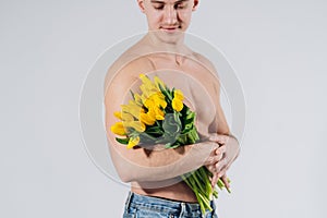 Man man with naked torso gives flowers. Romantic Man with bouquet of tulips for birthday. Happy woman`s day. Giving