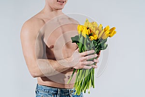 Man man with naked torso gives flowers. Romantic Man with bouquet of tulips for birthday. Happy woman`s day. Giving