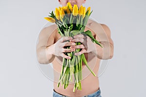 Man man with naked torso gives flowers. Romantic Man with bouquet of tulips for birthday. Happy woman`s day. Giving