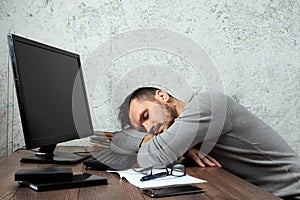 A man, a man sitting at a table in the office, and not working, tired look. The concept of office work, laziness fatigue