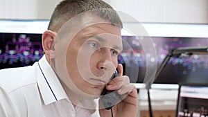 Man manager working in control room of electric power station calls on phone.