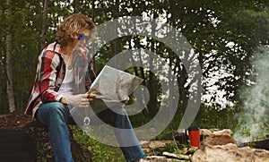 Man with map sits in front of bonfire