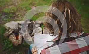 Man with map sits in front of bonfire