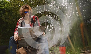 Man with map sits in front of bonfire