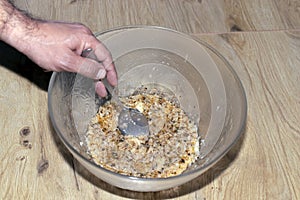 man marinates meat, stirs with spoon.