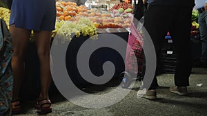 A man at the market packs food into a large bag on wheels.