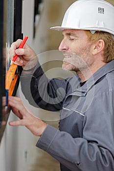 man marking off window frame