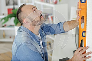 man marking on wall with level