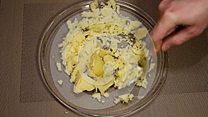 Man mashes potatoes in a glass bowl