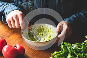 Man mashing avocado in bowl