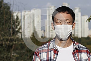 The man in the mask on the background of the city, concept of air pollution and viral infection