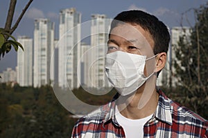 The man in the mask on the background of the city, concept of air pollution and viral infection