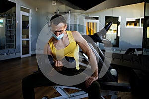 Man With Mask Doing Biceps Exercises With Dumbbells In The Gym.