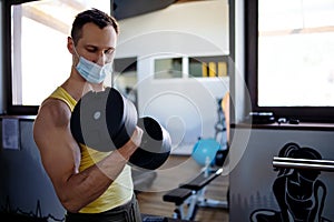 Man With Mask Doing Biceps Exercises With Dumbbells In The Gym.