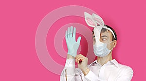 Man in mask Easter Bunny and medical mask puts on gloves, virus or coronavirus protection before holiday