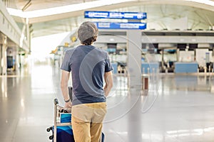 Man in mask at empty airport at check in in coronavirus quarantine isolation, returning home, flight cancellation