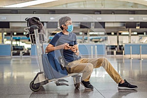 Man in mask at empty airport at check in in coronavirus quarantine isolation, returning home, flight cancellation