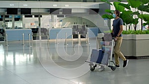 Man in mask at empty airport at check in in coronavirus quarantine isolation, returning home, flight cancellation